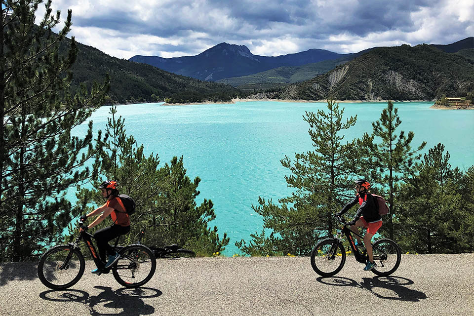vacances sportives 2 vélos électriques devant un lac bleu turquoise